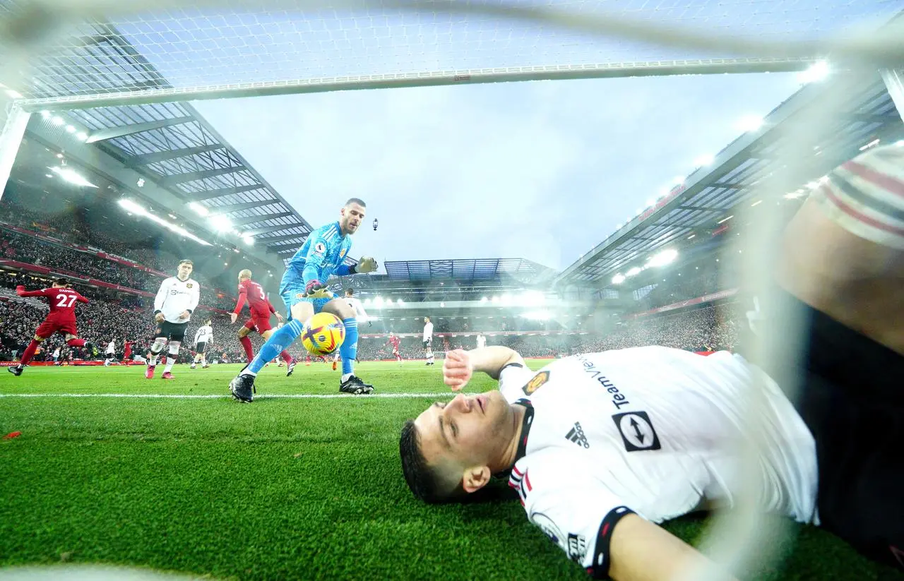 Diogo Dalot lies on the floor in the goal after another Liverpool strike is celebrated