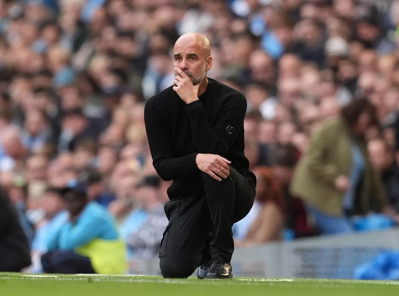 Manchester City manager Pep Guardiola kneels with his chin in his hand