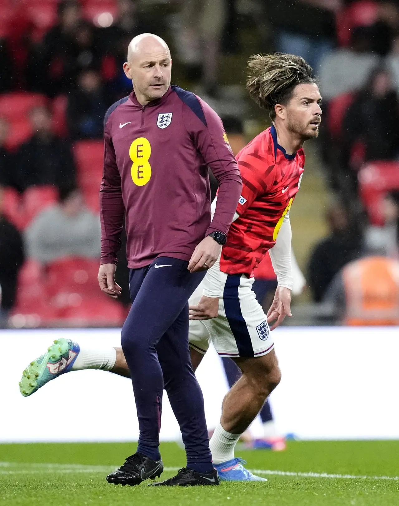 England’s Jack Grealish, right, sprints behind manager Lee Carsley in the warm-up ahead of the Nations League game against Finland