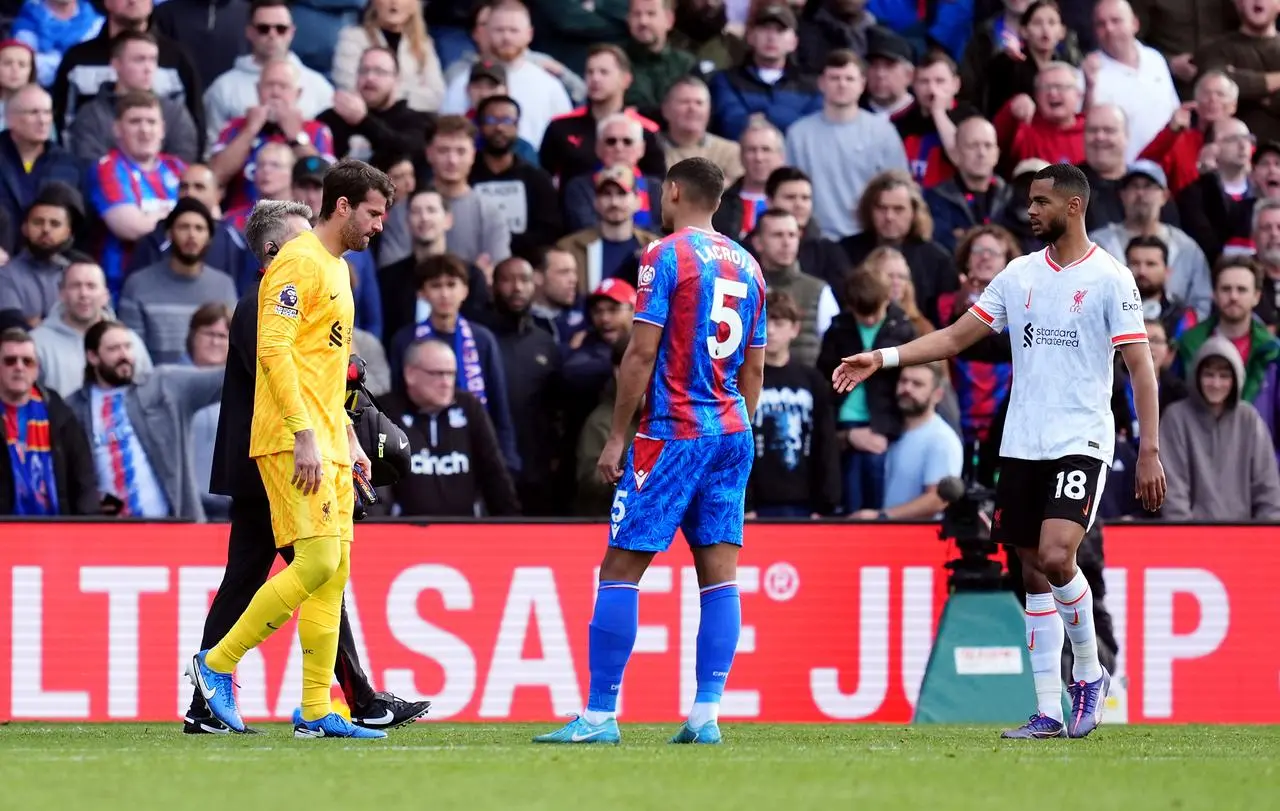 Liverpool goalkeeper Alisson Becker, left, walks off the pitch injured against Crystal Palace