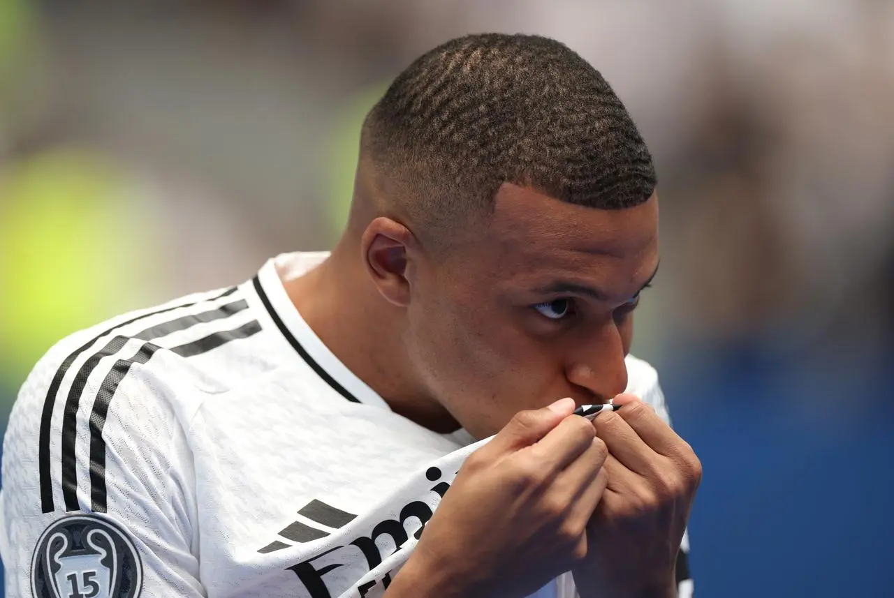 Kylian Mbappe kisses the Real Madrid badge at his unveiling