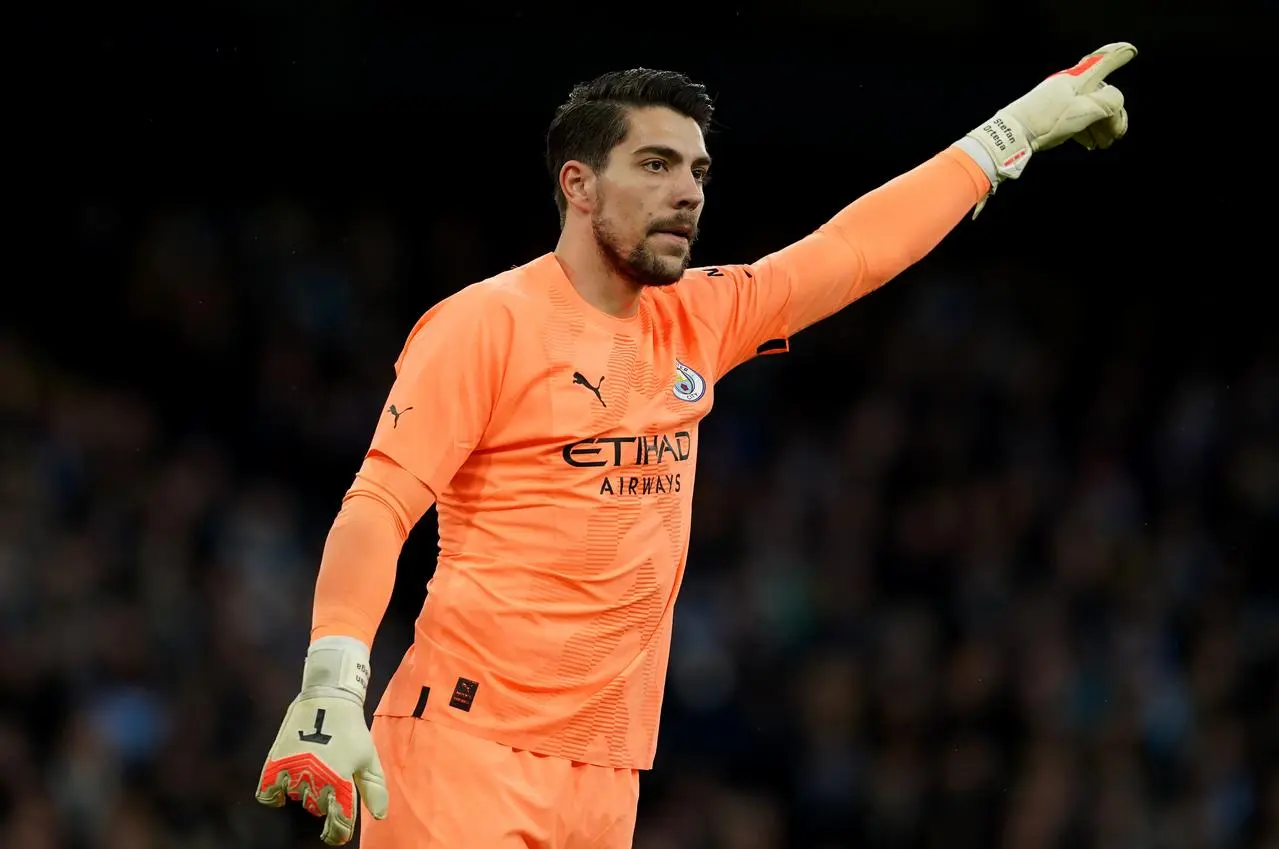 Manchester City goalkeeper Stefan Ortega gestures to a team-mate during a match, pointing upwards