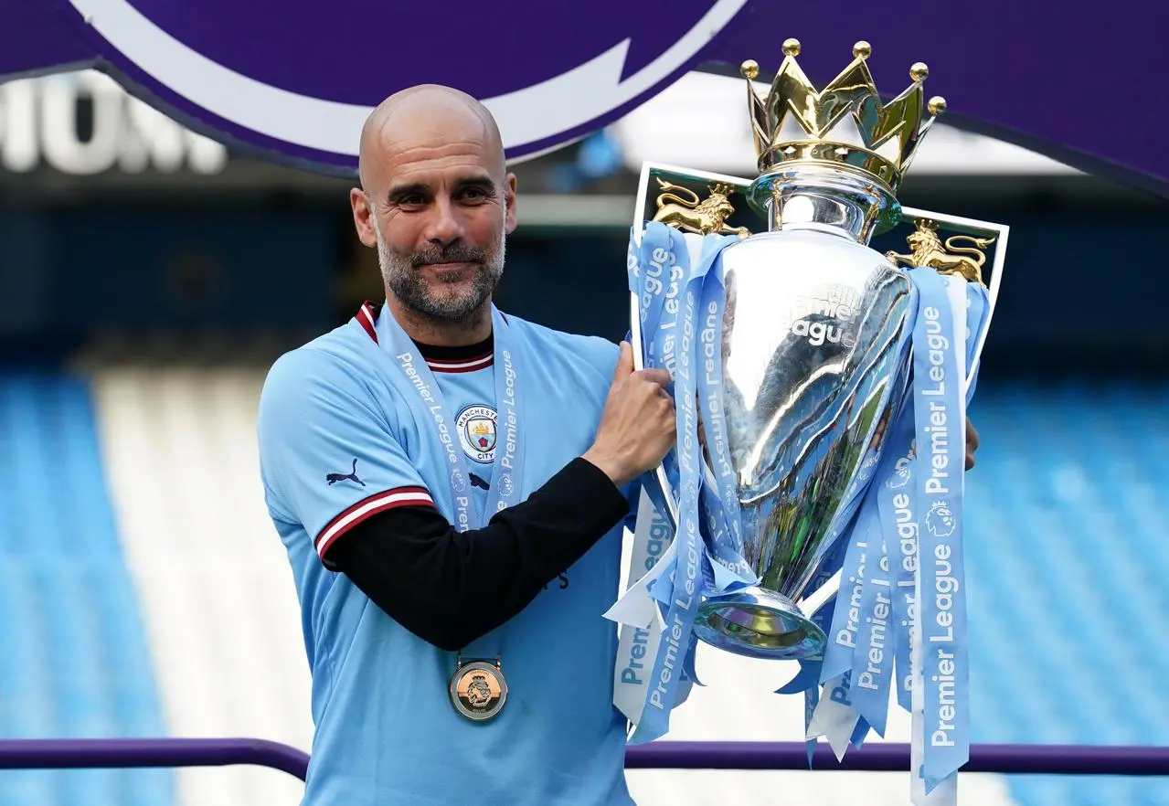 Pep Guardiola poses with the Premier League trophy