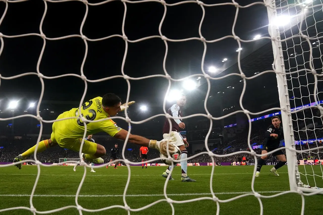 Aston Villa goalkeeper Emiliano Martinez dives low to his right to claw the ball off the line