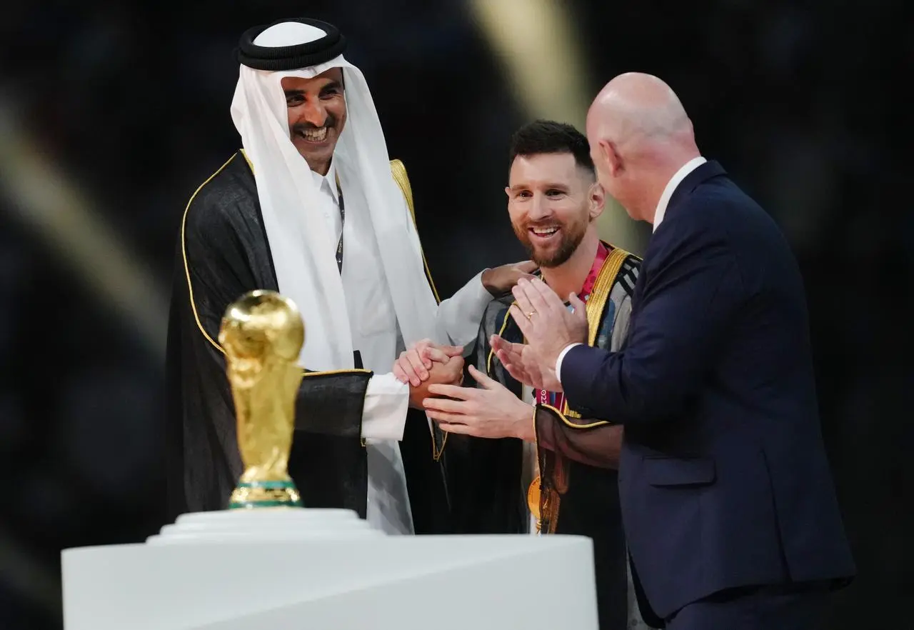 Lionel Messi, centre, stands in front of the World Cup trophy, flanked by the Emir of Qatar, left, and FIFA president Gianni Infantino, right