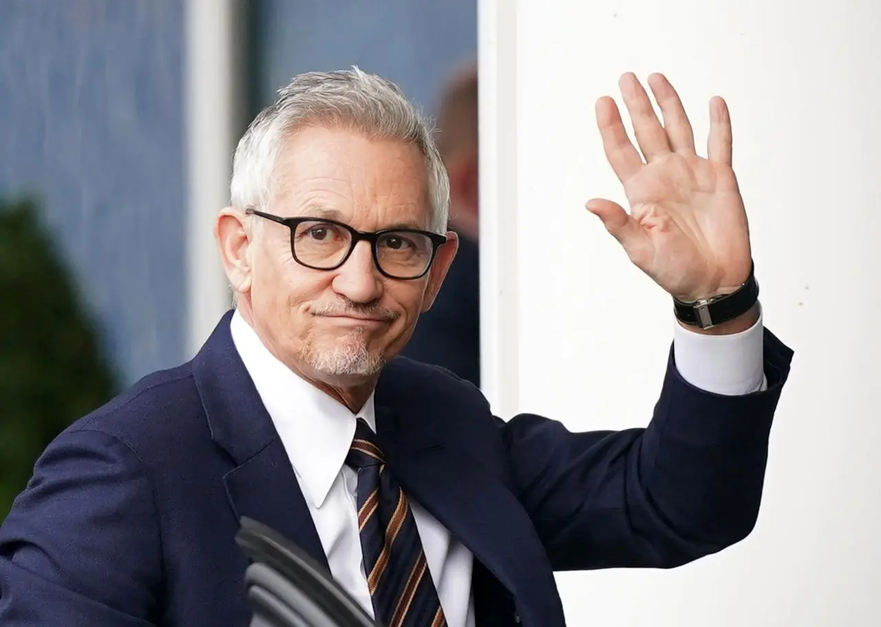 Gary Lineker waves while dressed in a suit and tie