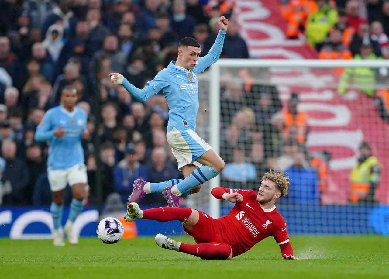 Manchester City's Phil Foden jumps over a challenge from Liverpool's Harvey Elliott