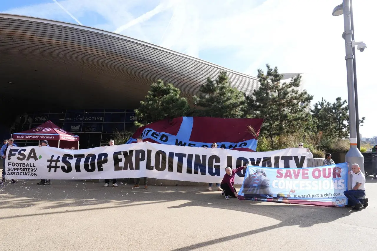 Fans hold up an FSA banner reading “Stop Exploiting Loyalty”