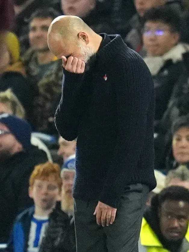 Manchester City manager Pep Guardiola hold his head in his right hand as his team lose to Brighton