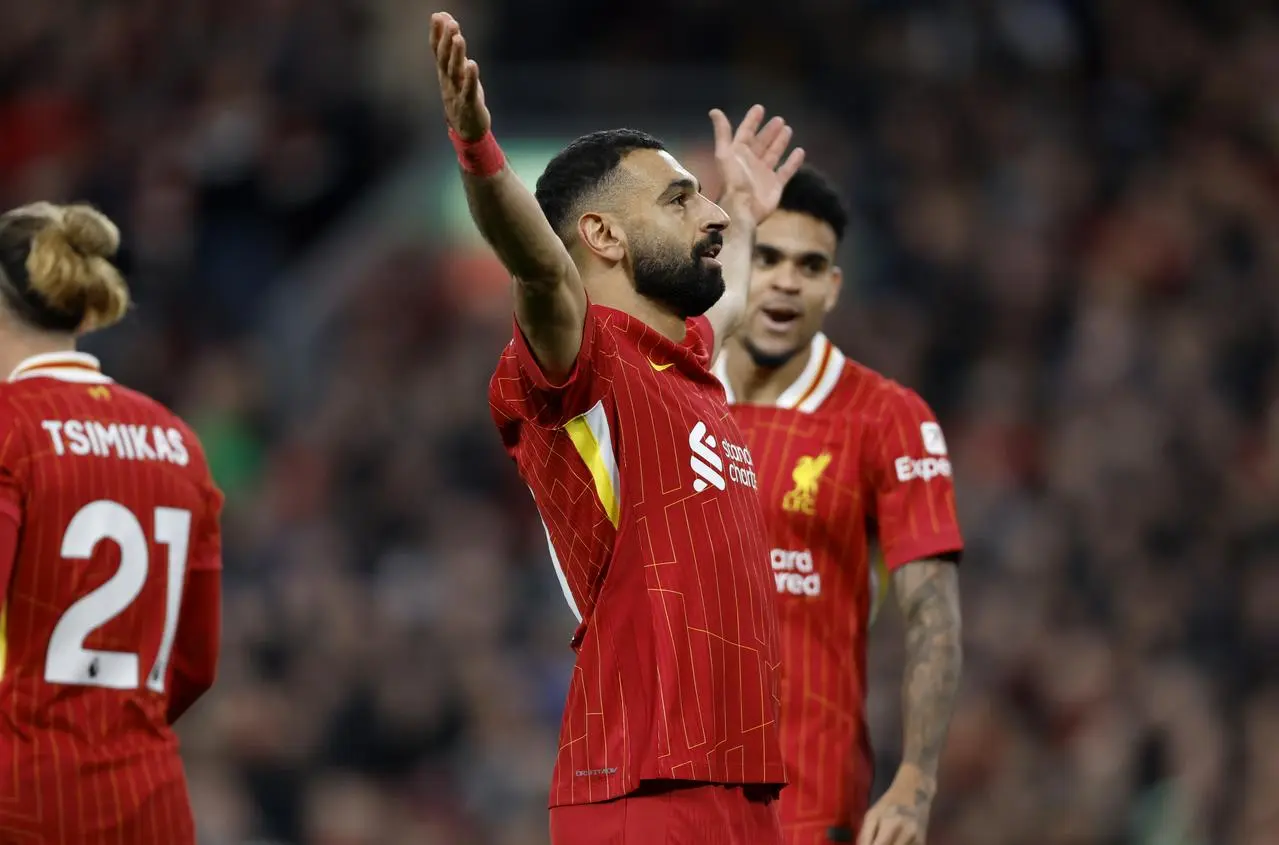 Mohamed Salah celebrates by raising both arms into the air