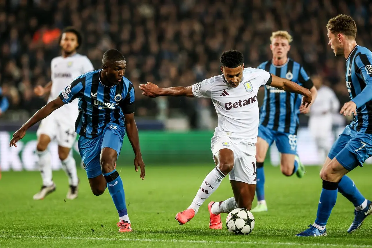 Ollie Watkins attempts to dribble the ball past two Club Brugge players