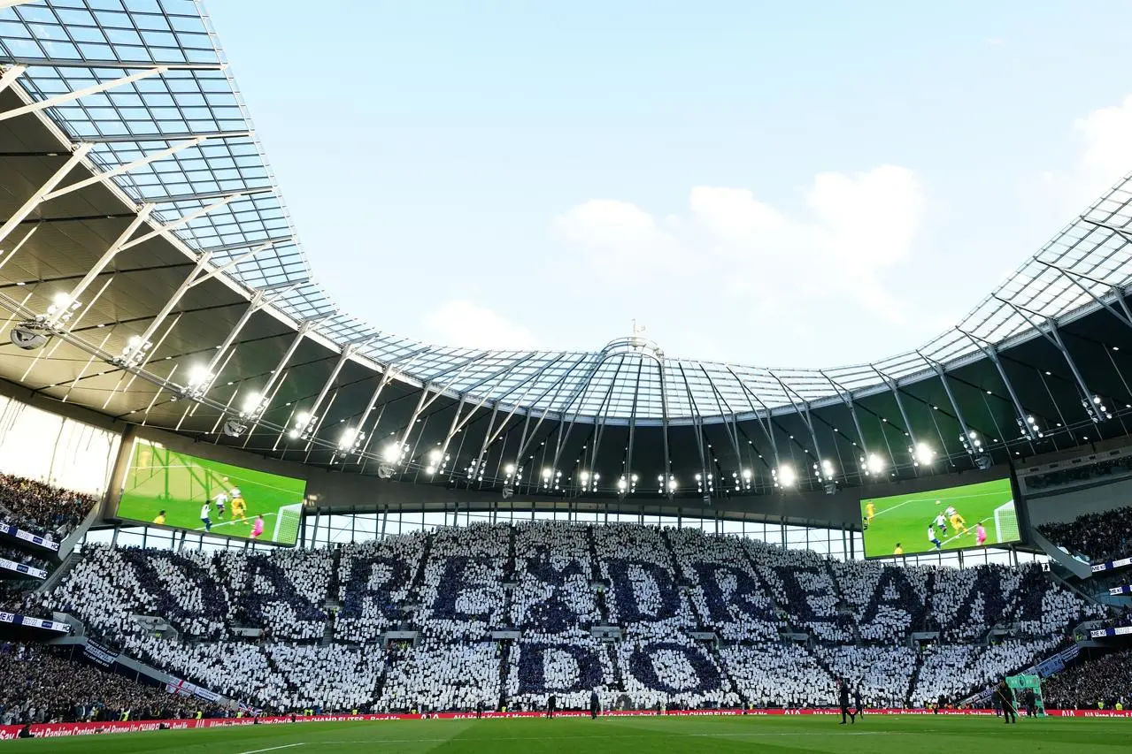 Tottenham fans in the stands hold up tiles that read “Dare Dream Do” in the stands