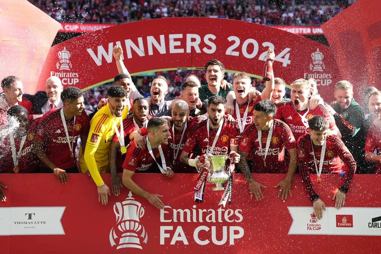 Manchester United captain Bruno Fernandes holds the trophy as he and his team celebrate winning the FA Cup at Wembley