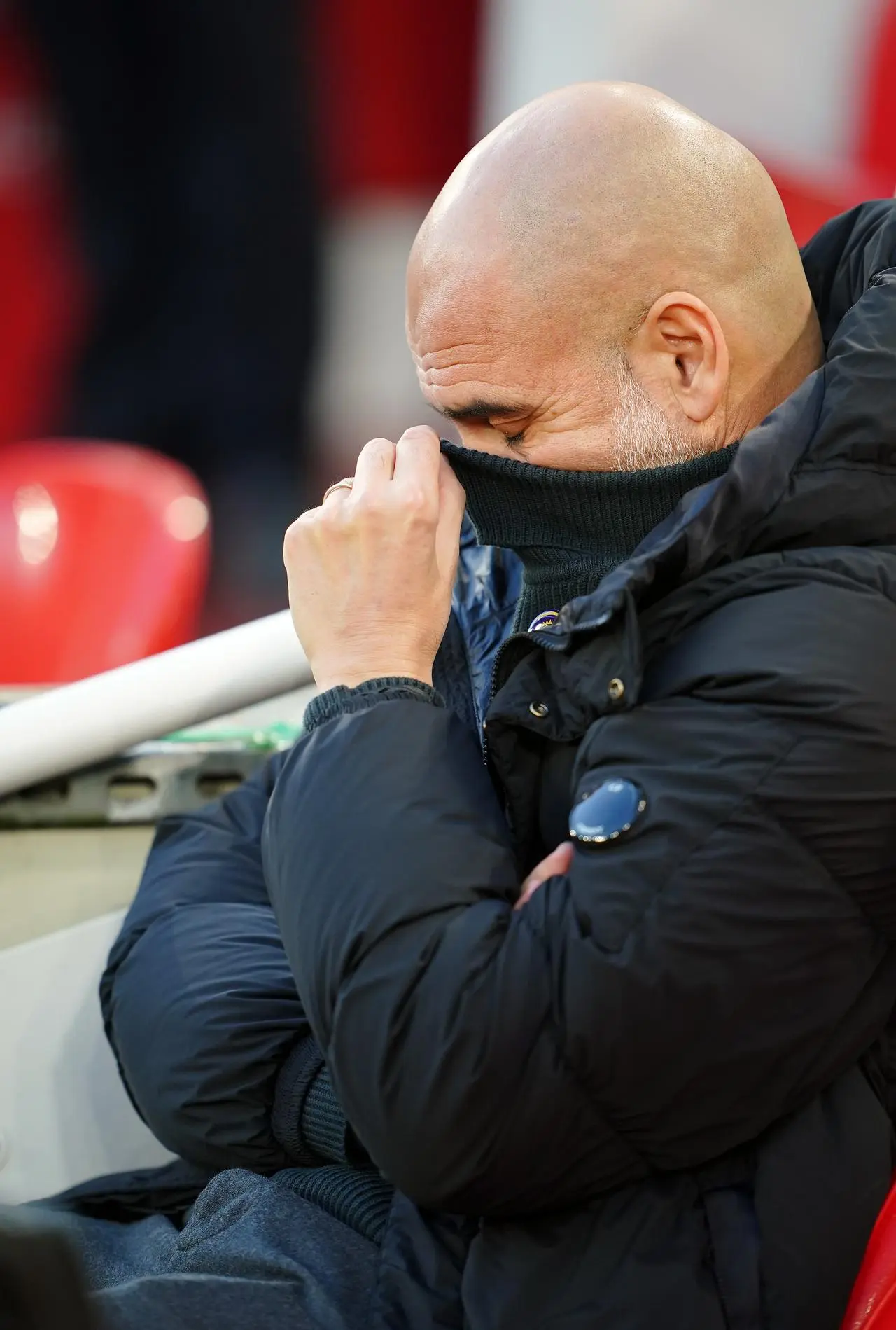 Pep Guardiola sinks his face into his polo neck jumper during Manchester City's defeat to Liverpool