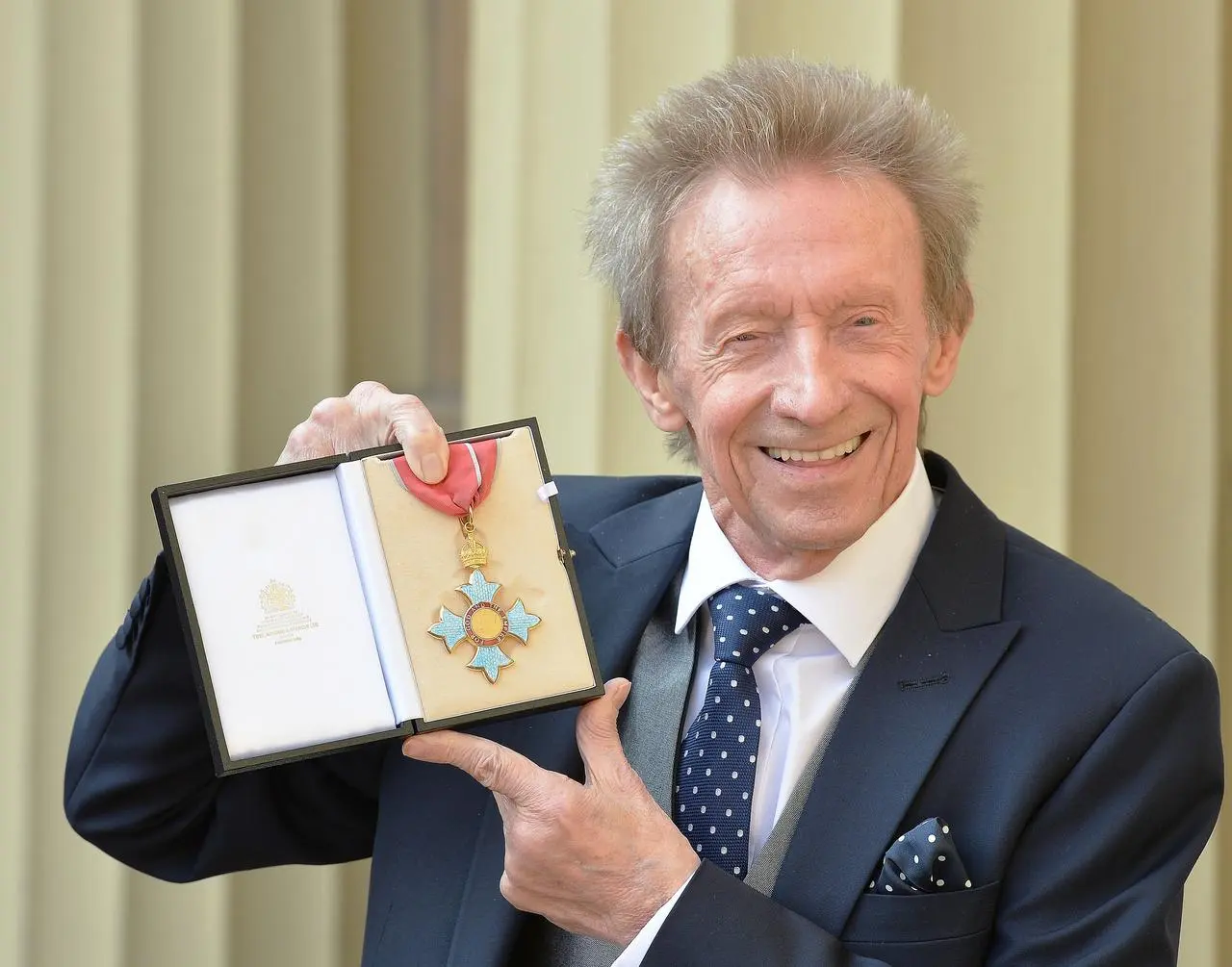 Denis Law holding his Commander of the Order of the British Empire (CBE) medal