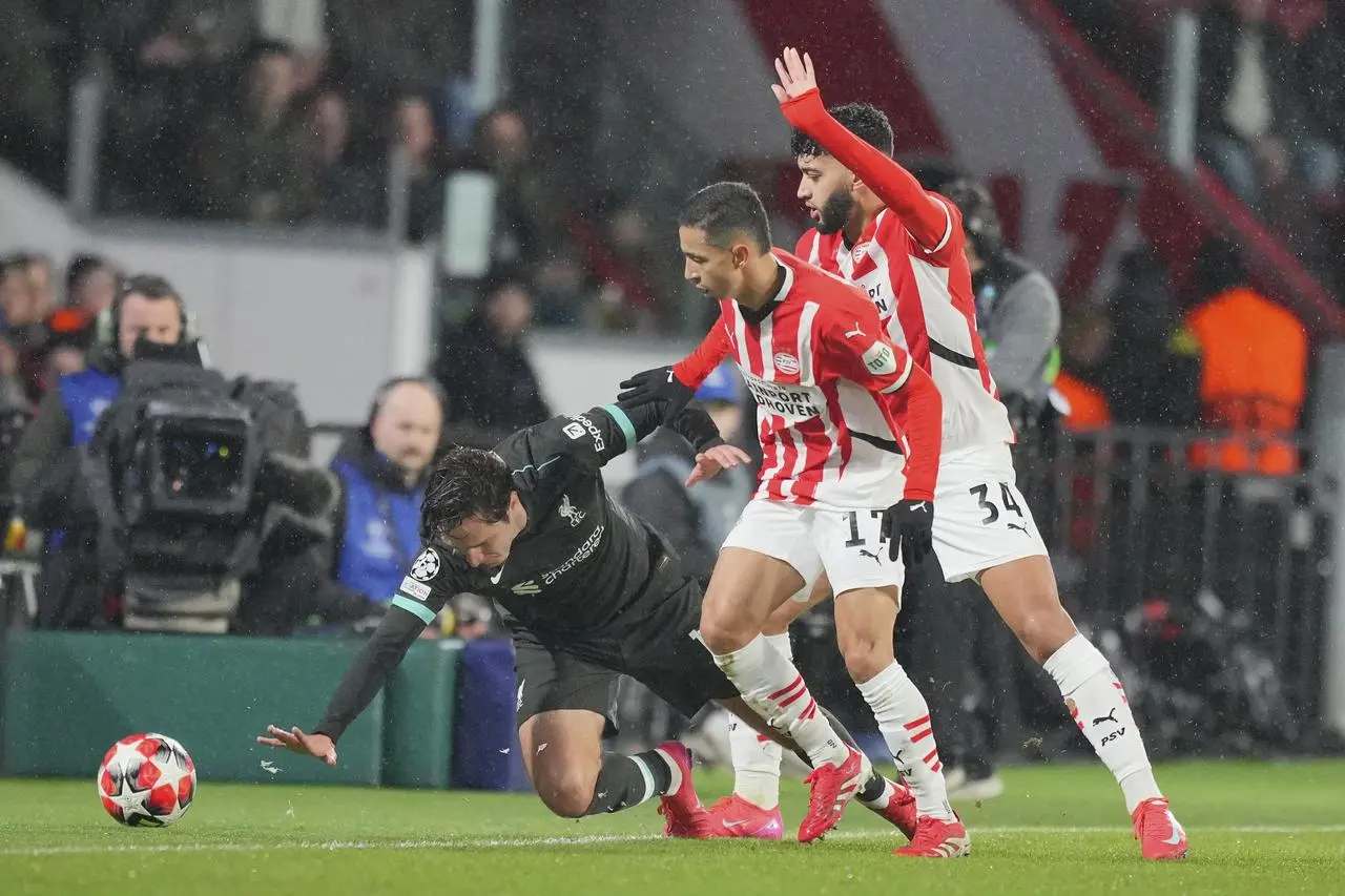 Liverpool’s Federico Chiesa falls in front of PSV’s Mauro Junior and Ismael Saibari