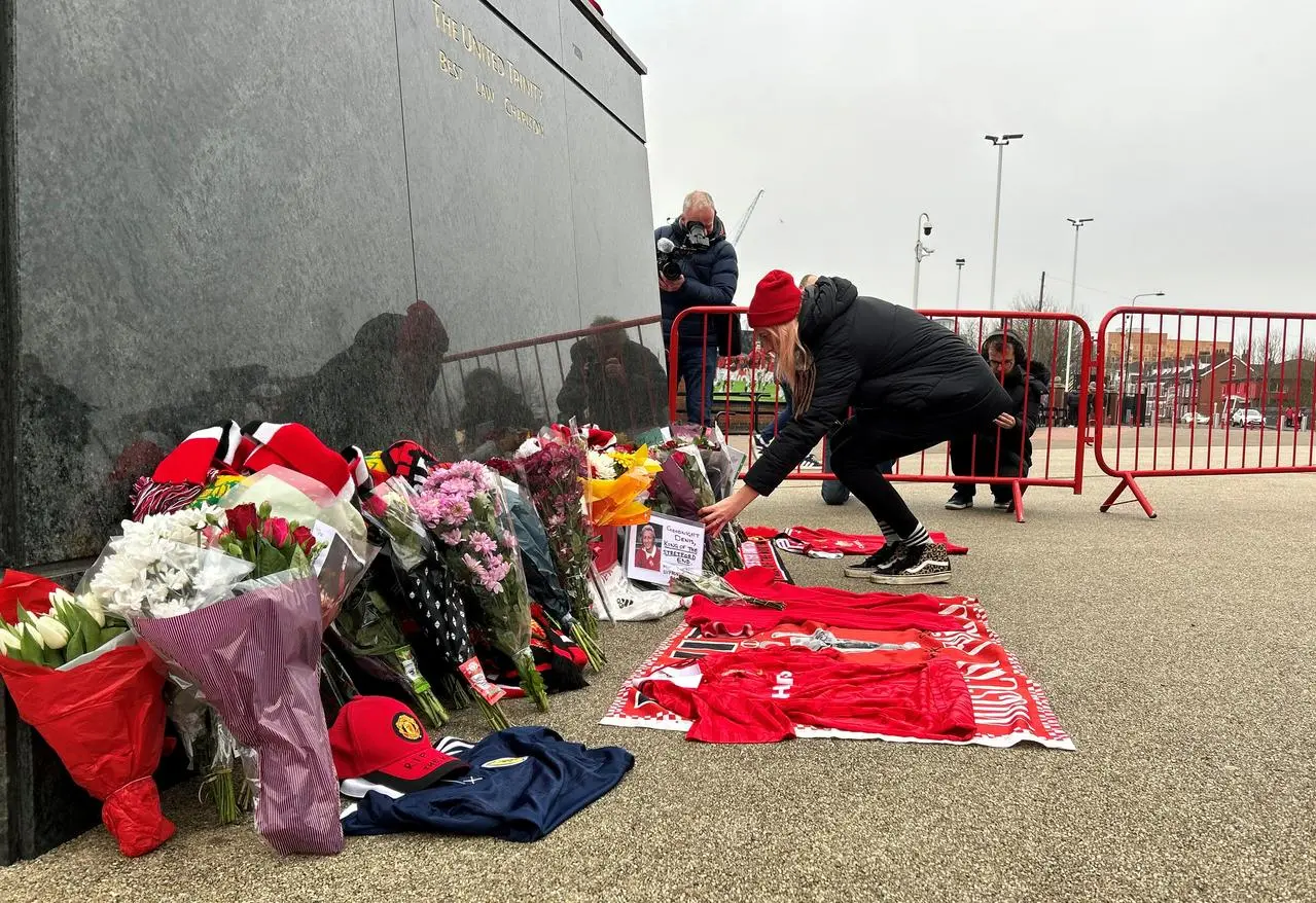 Tributes are laid to Denis Law at the United Trinity statue outside Old Trafford