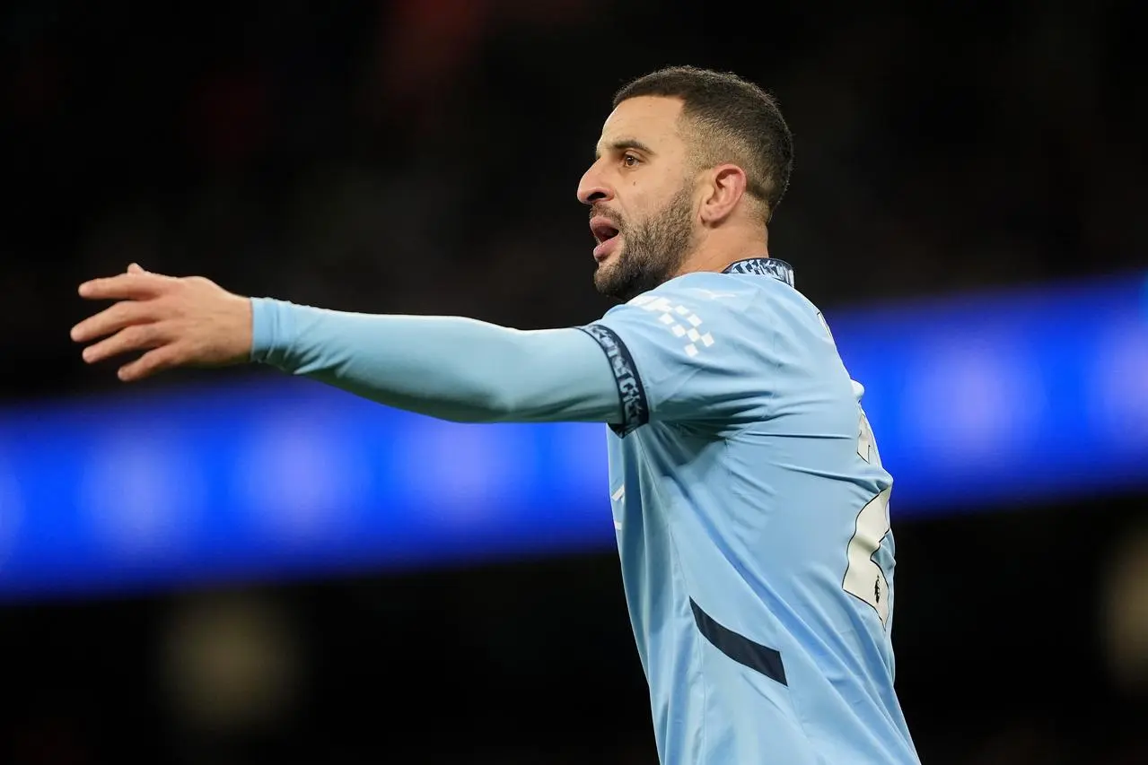 Kyle Walker reaches out his left arm during a game for Manchester City