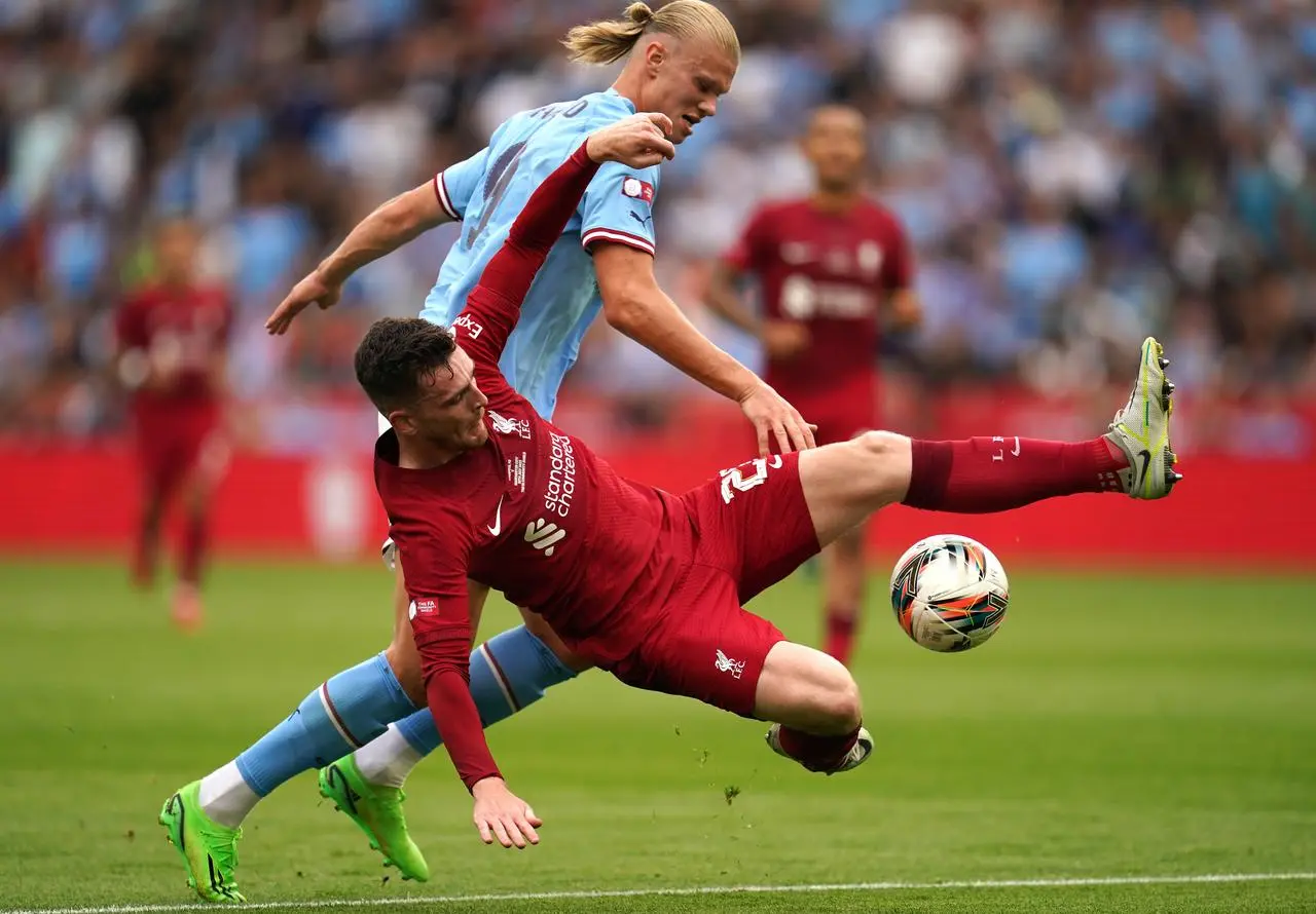 Liverpool's Andy Robertson, front, puts in a tackle on Manchester City’s Erling Haaland 