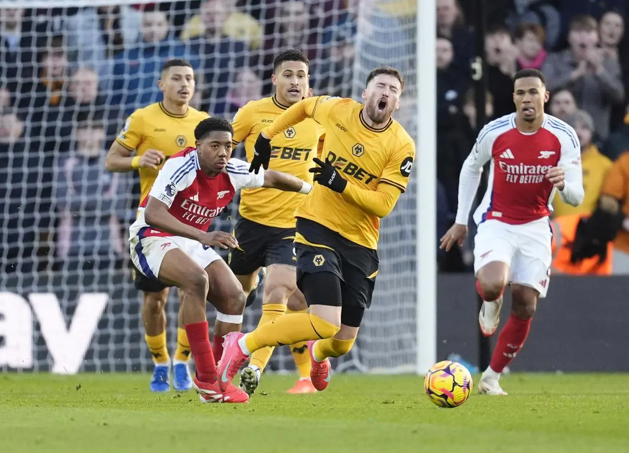 Wolves Matt Doherty, foreground, falls to the ground after being fouled by Arsenal's Myles Lewis-Skelly, left