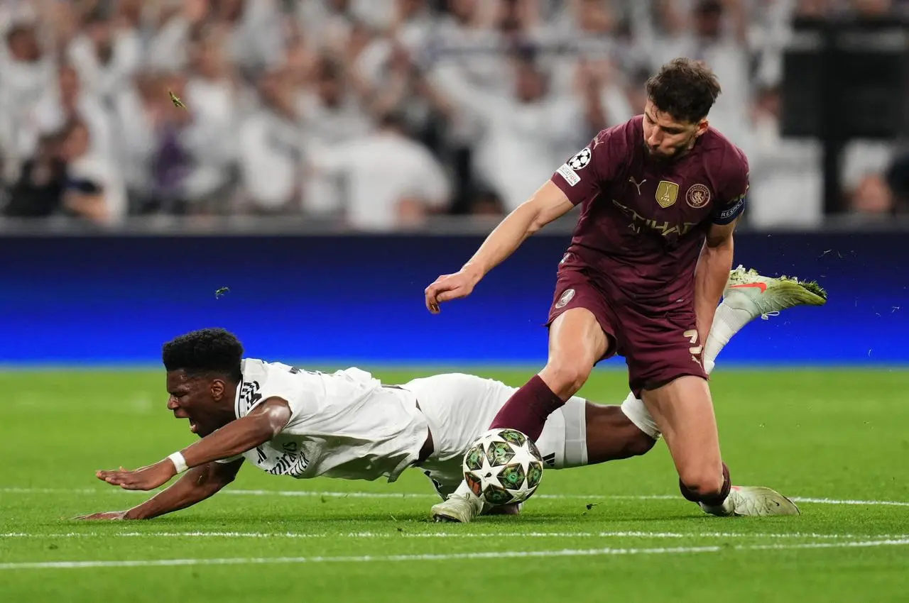 Manchester City's Ruben Dias wins the ball in a challenge with Aurelien Tchouameni 