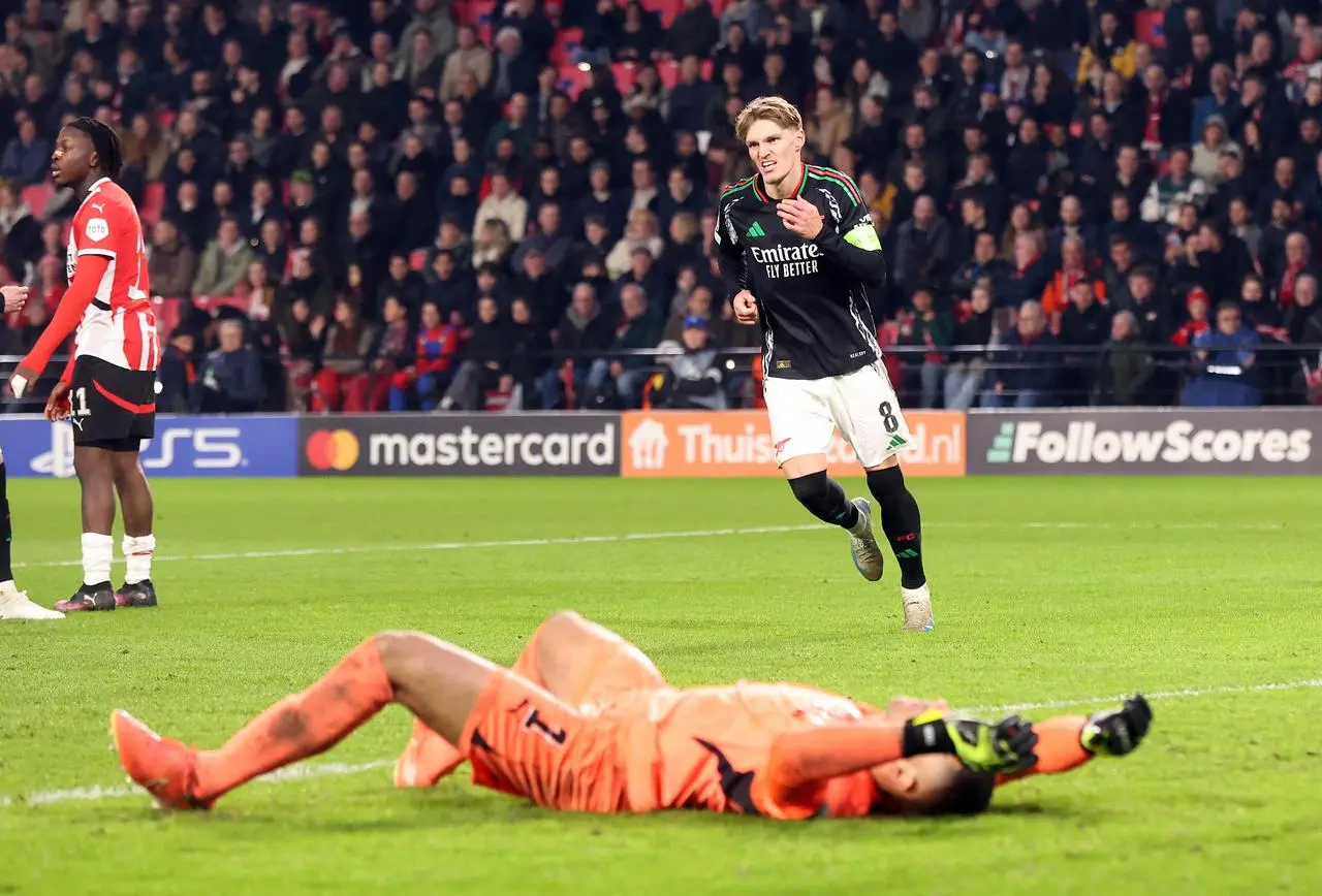 Arsenal’s Martin Odegaard celebrates his second goal with PSV Eindhoven keeper Walter Benitez on the ground