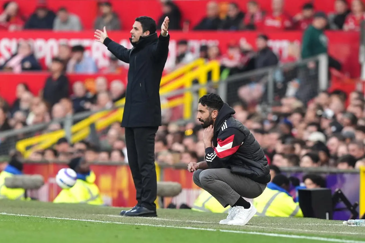 Manchester United manager Ruben Amorim, right, crouches on the touchline while Arsenal boss Mikel Arteta stands with his arms outstretched