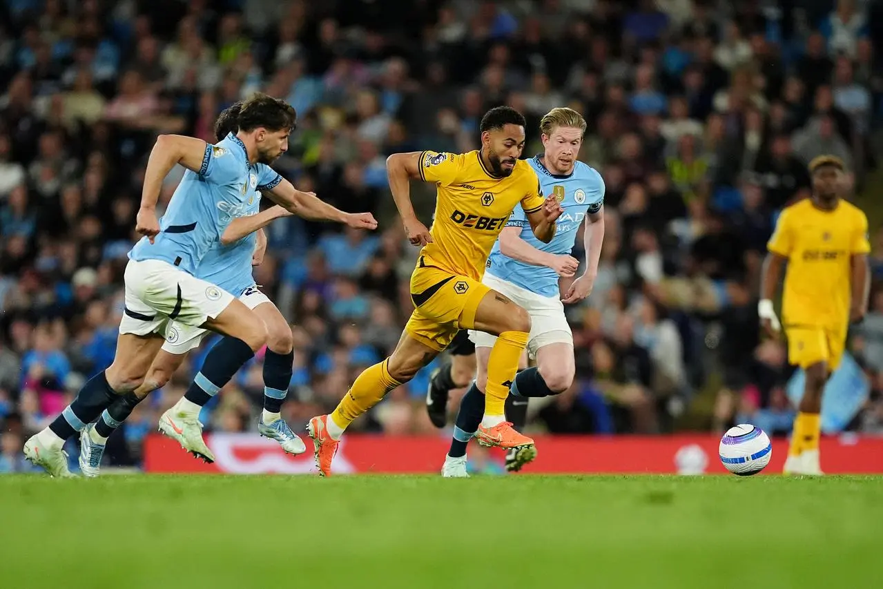 Matheus Cunha runs away from multiple Manchester City players