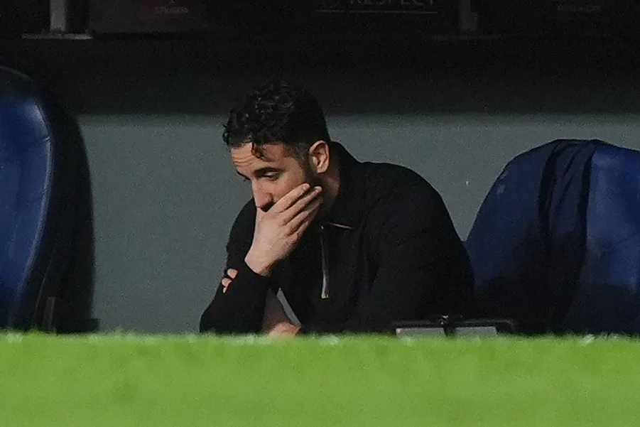 Manchester United manager Ruben Amorim sit in the dugout resting his chin in his hand