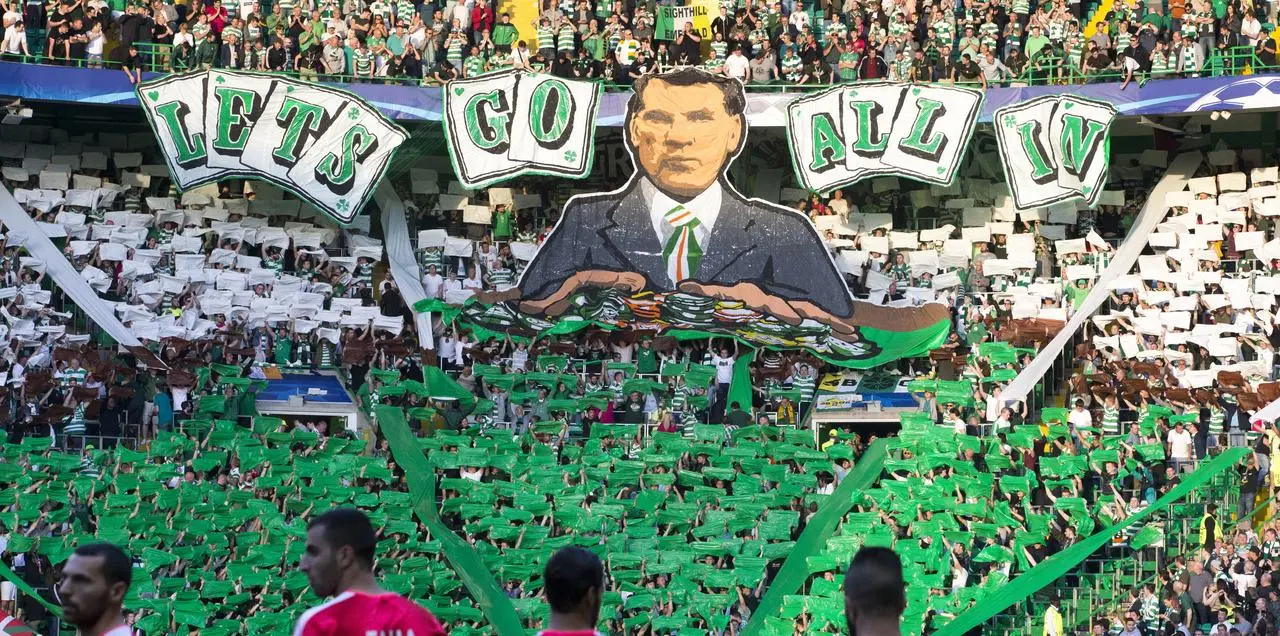Celtic fans with a banner of Brendan Rodgers which says 'Let's Go All In'