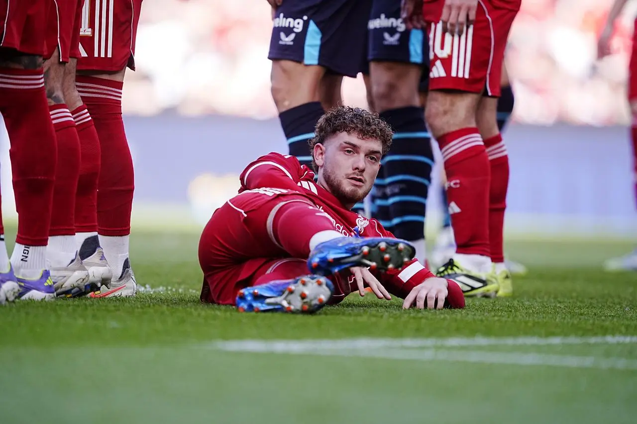 Liverpool's Harvey Elliott lies on the floor behind the defensive wall
