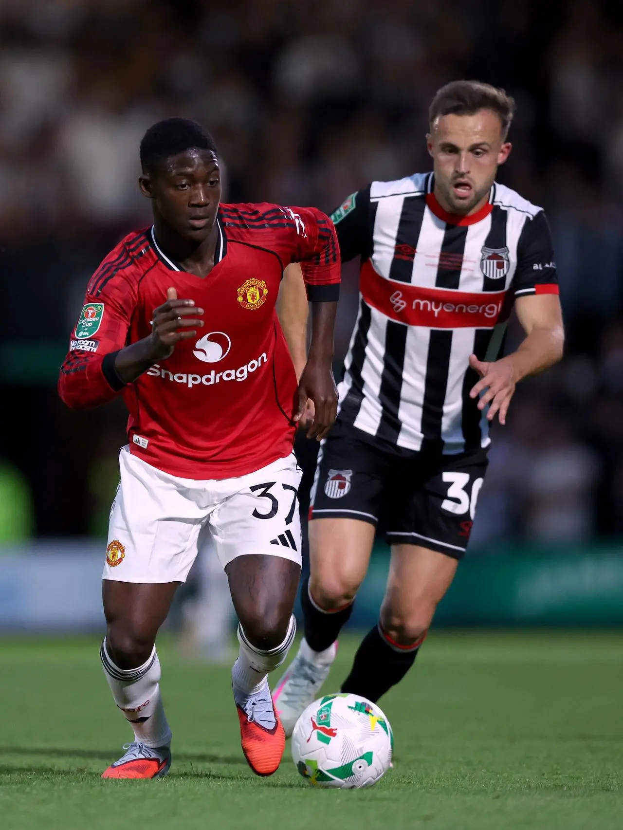 Manchester United’s Kobbie Mainoo, left, takes on Grimsby's Charles Vernam