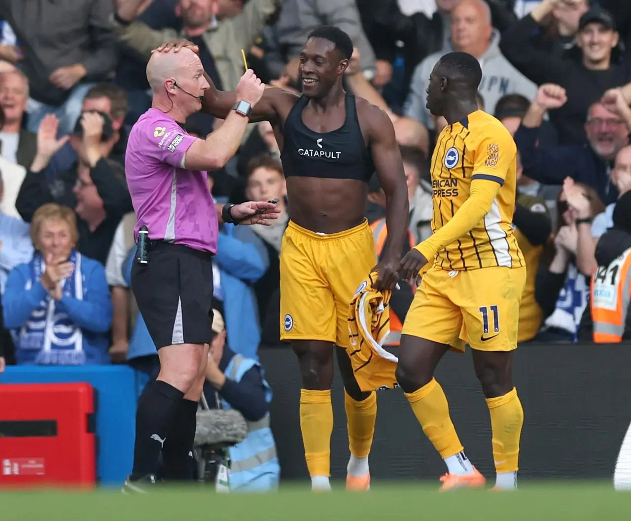 Brighton’s Danny Welbeck (centre) pats the head of referee Simon Hooper as he gives him a yellow card