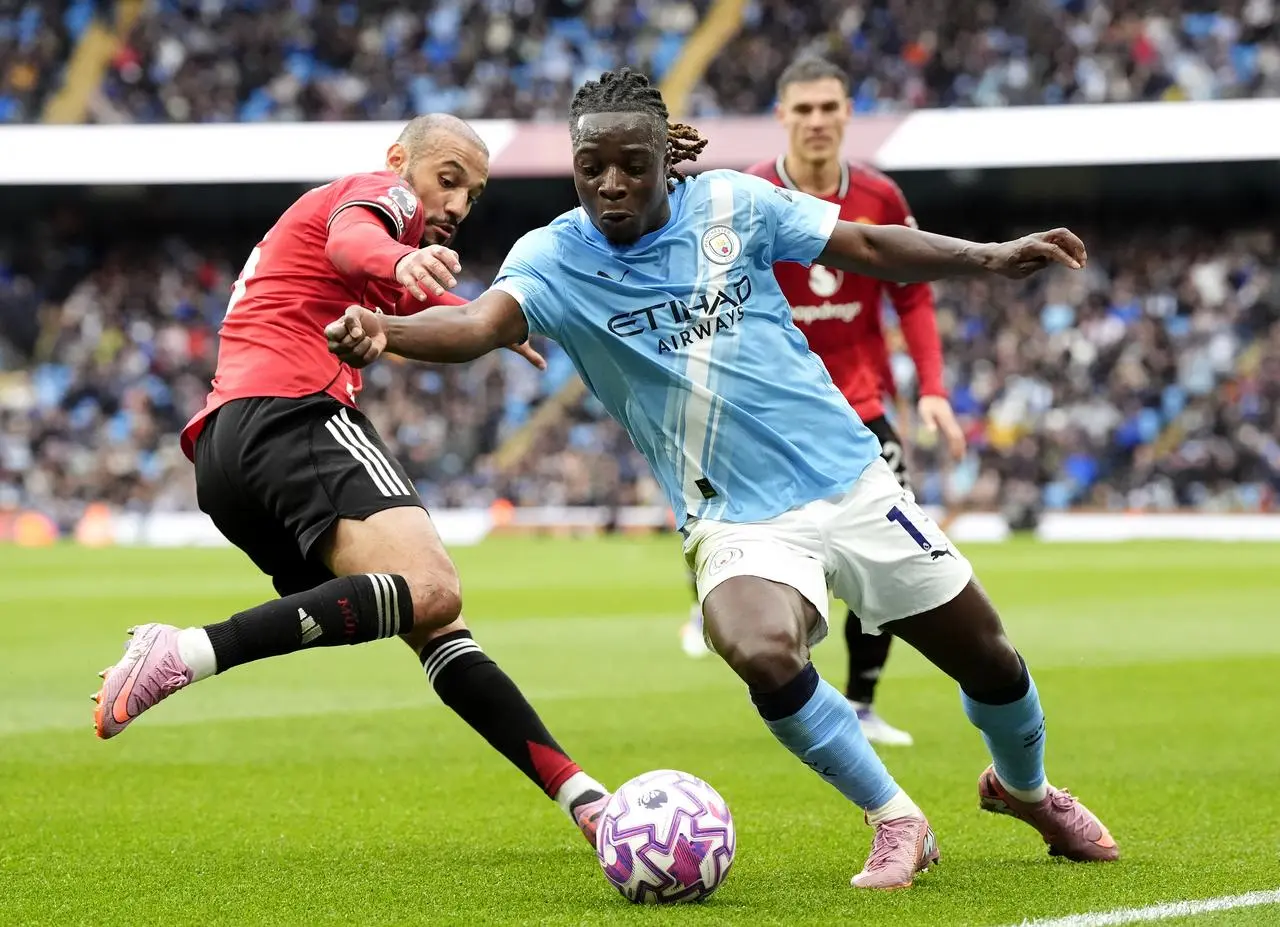 Manchester United’s Noussair Mazraoui, left, tackles Manchester City’s Jeremy Doku