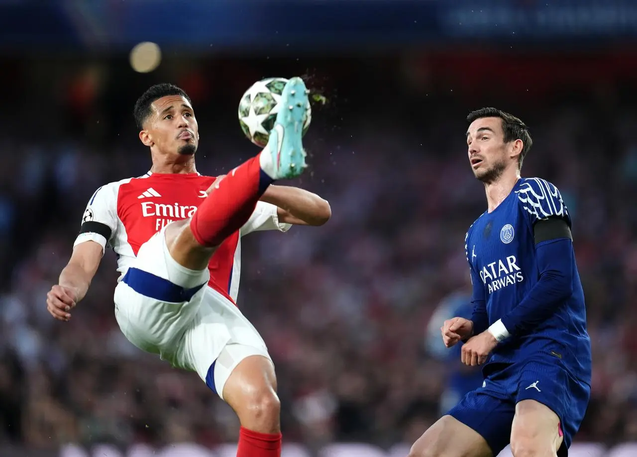 Arsenal’s William Saliba, left, clears the ball over his shoulder and away from Paris St Germain’s Fabian Ruiz