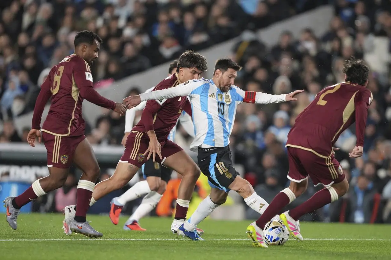 Argentina’s Lionel Messi dribbles chased by Venezuela’s Cristian Casseres, left