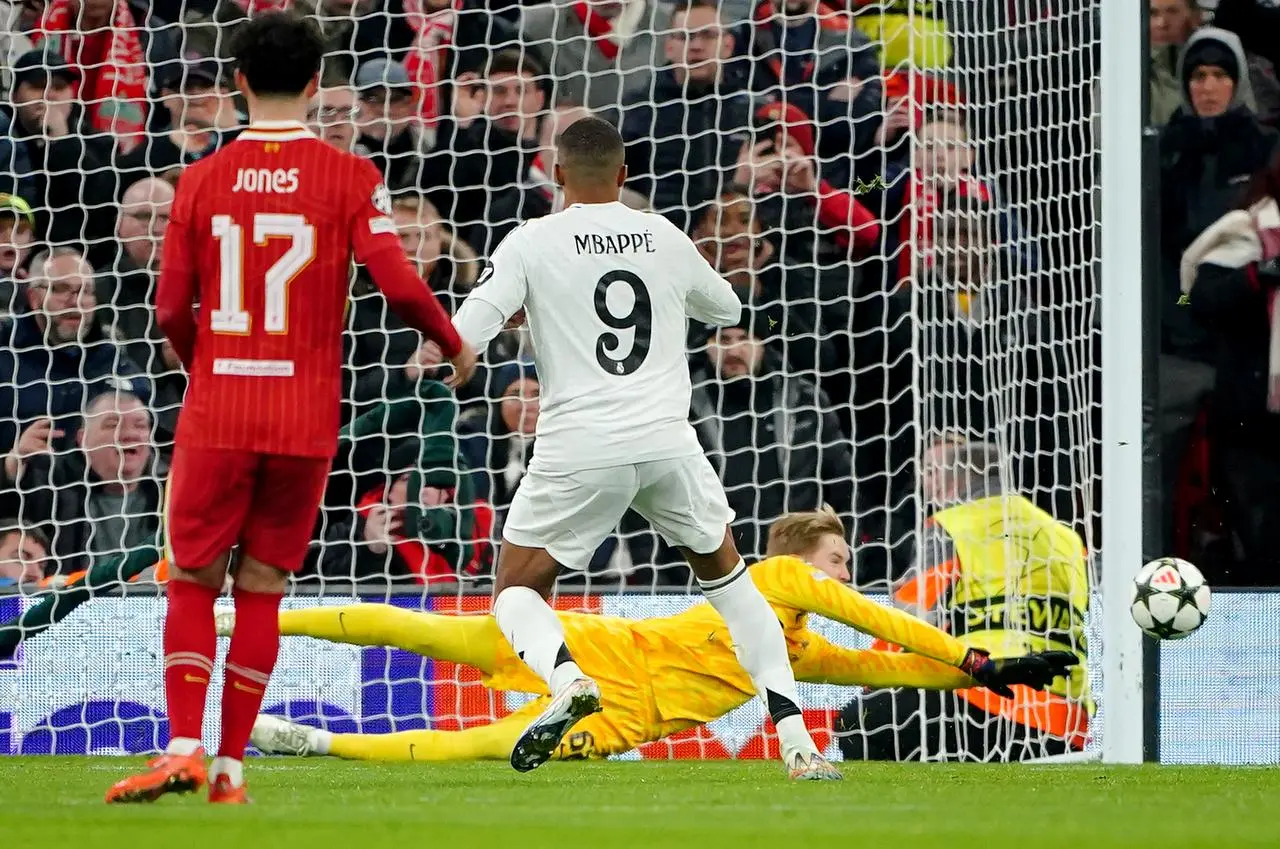 Liverpool goalkeeper Caoimhin Kelleher, rear, saves a penalty from Real Madrid’s Kylian Mbappe, right