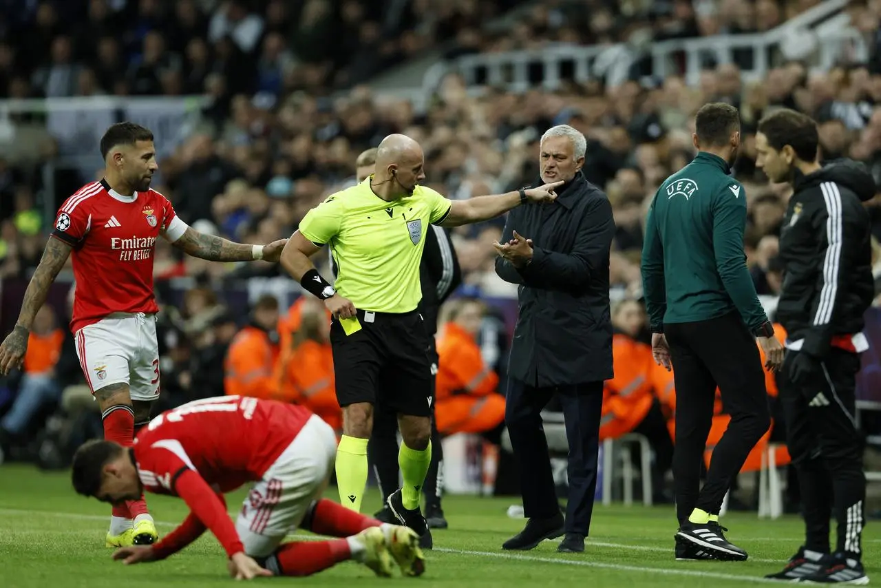 Benfica manager Jose Mourinho (centre right) applauds on the touchline as referee Szymon Marciniak shows a yellow card in the direction of the Benfica benc