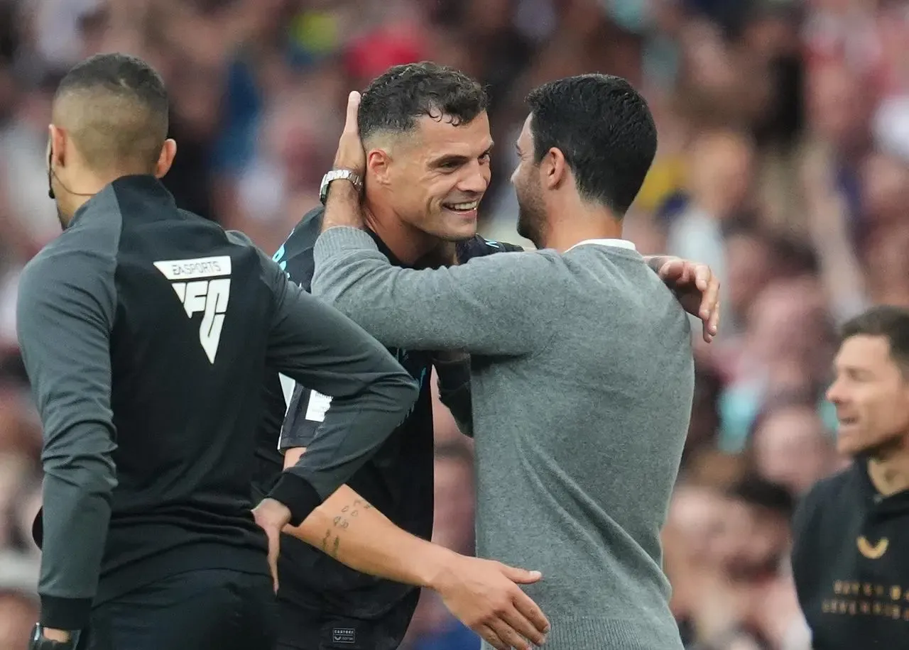 Bayer Leverkusen’s Granit Xhaka (left) embraces Arsenal manager Mikel Arteta