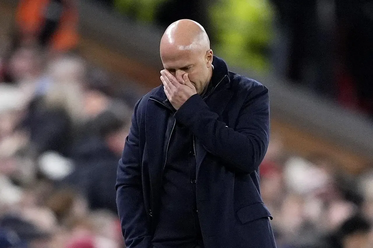 Arne Slot covers his face with his hand on the touchline